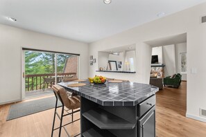 A modern kitchen with a large island, a dining area with a view, and a cozy living space with a fireplace.