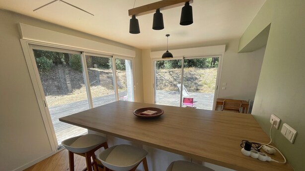 A modern kitchen with a large island, bar stools, and a view of the outdoors. - Villa in the pines near the beach, parking and pets allowed (La Tranche-sur-Mer)