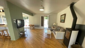 A living room with a TV, a sofa, a coffee table, and a fireplace. - Villa in the pines near the beach, parking and pets allowed (La Tranche-sur-Mer)