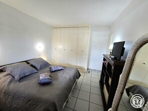 A bedroom with a bed, pillows, a TV, and a wardrobe. - House by the water, pets welcome - 4 guests (Bergerac)