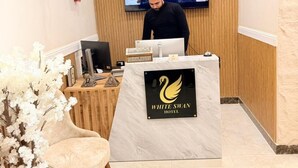 A reception desk with a swan logo, a television screen, and a wooden panel wall. - white swan hotel (Cairo)