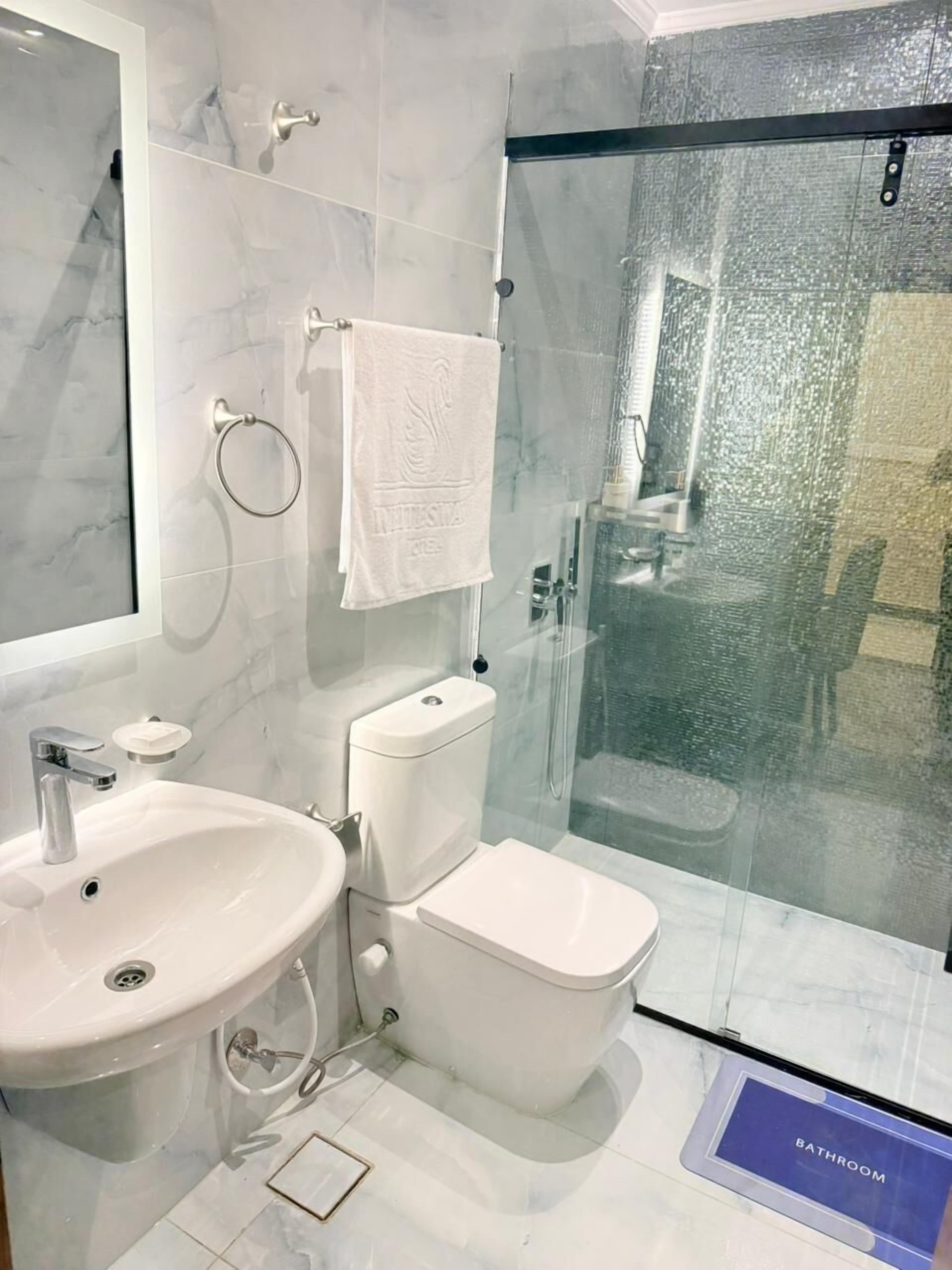 Un baño moderno con cabina de ducha de vidrio, un lavabo blanco y un inodoro.