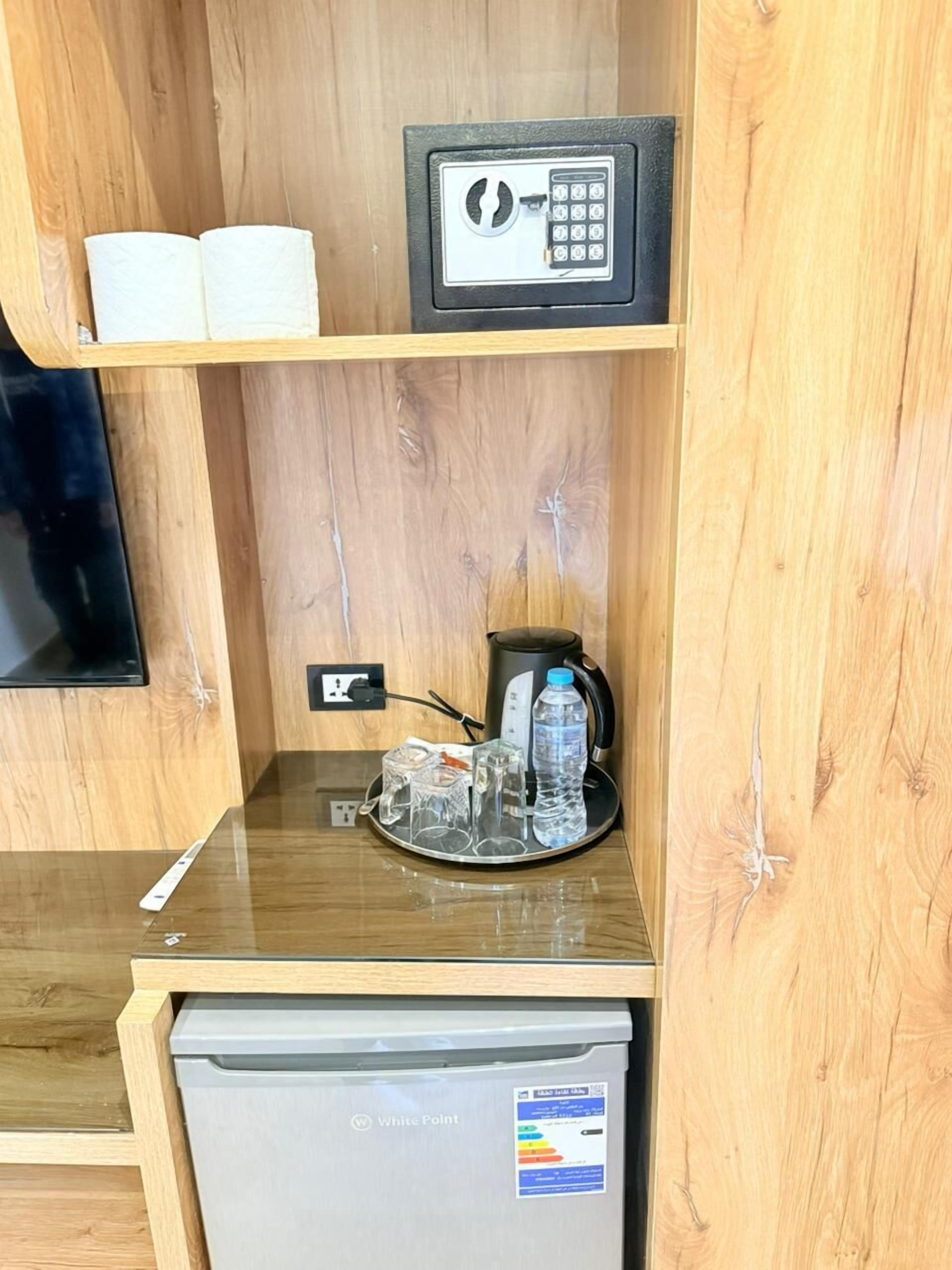 A wooden-framed room with a minibar, a microwave, a small refrigerator, and a water bottle on the counter.