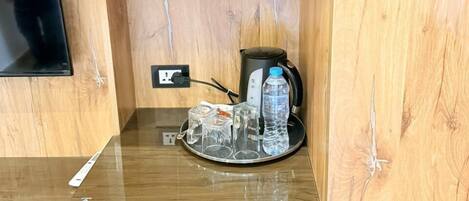 A wooden-framed room with a minibar, a microwave, a small refrigerator, and a water bottle on the counter.