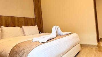 Habitación de hotel moderna con una cama grande, cabecera de madera y una luz ambiental cálida.