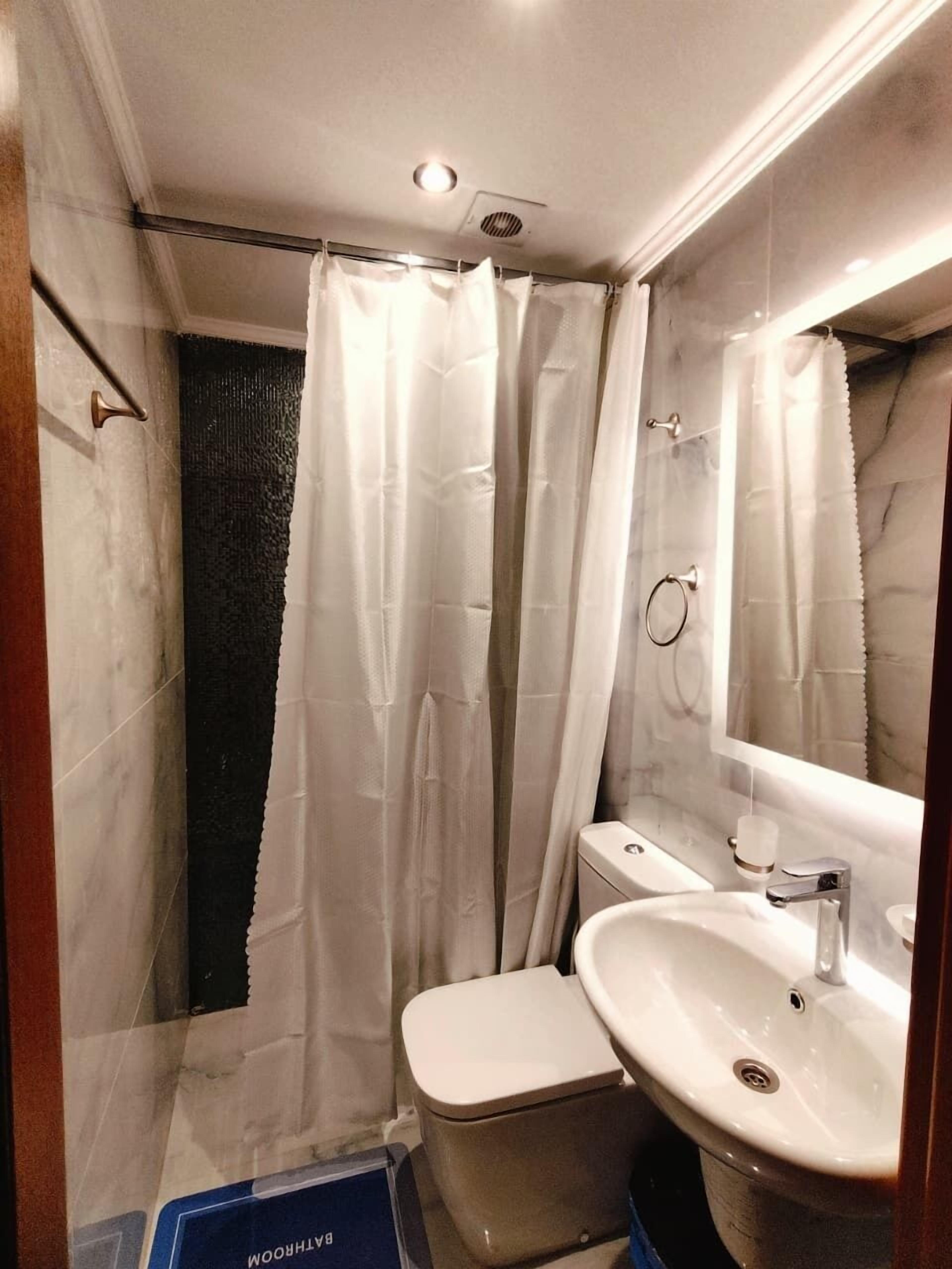 A bathroom with a shower curtain, a toilet, a sink, and a mirror.