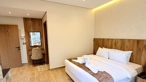 A modern hotel room with a large bed, wooden headboard, and a small bedside table. - white swan hotel (Cairo)