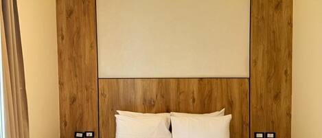 Une chambre d’hôtel avec un grand lit, une tête de lit en bois, des tables de chevet et un téléphone.