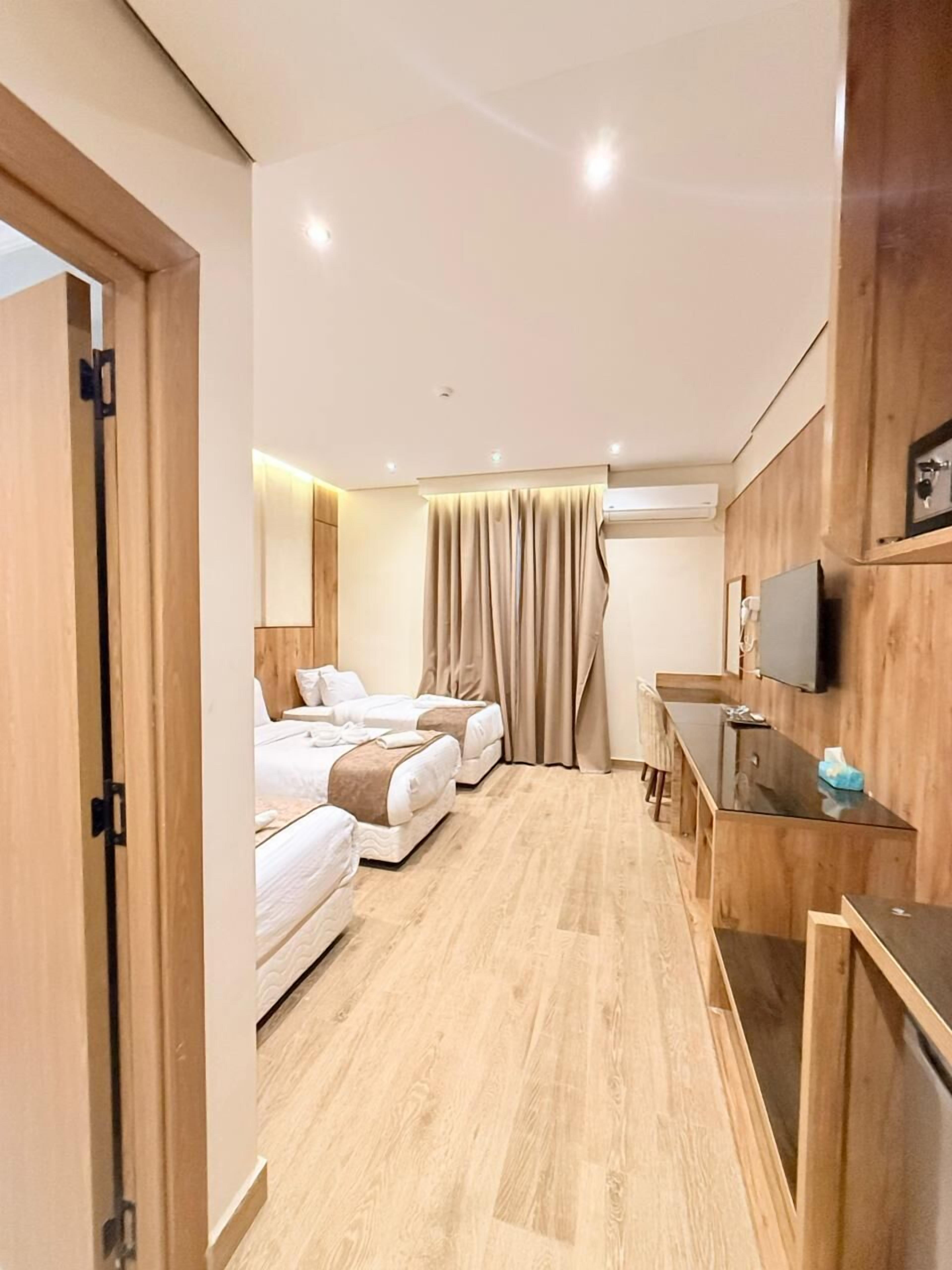 Ein Hotelzimmer mit zwei Betten, einem Schreibtisch, einem Fernseher und einem Kleiderschrank.