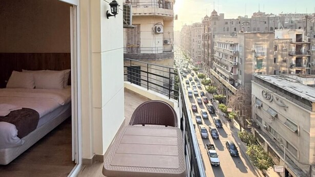 A balcony with a bed, a table, and a chair. - white swan hotel (Cairo)