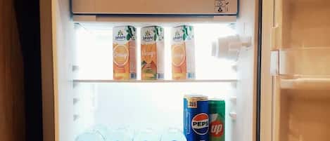 Un refrigerador abierto con estantes que contienen cartones de jugo, botellas de agua y una lata de Pepsi.
