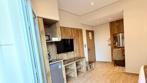 A modern interior with a kitchen area, a flat-screen TV, and a seating area with a chair and a table. - white swan hotel (Cairo)