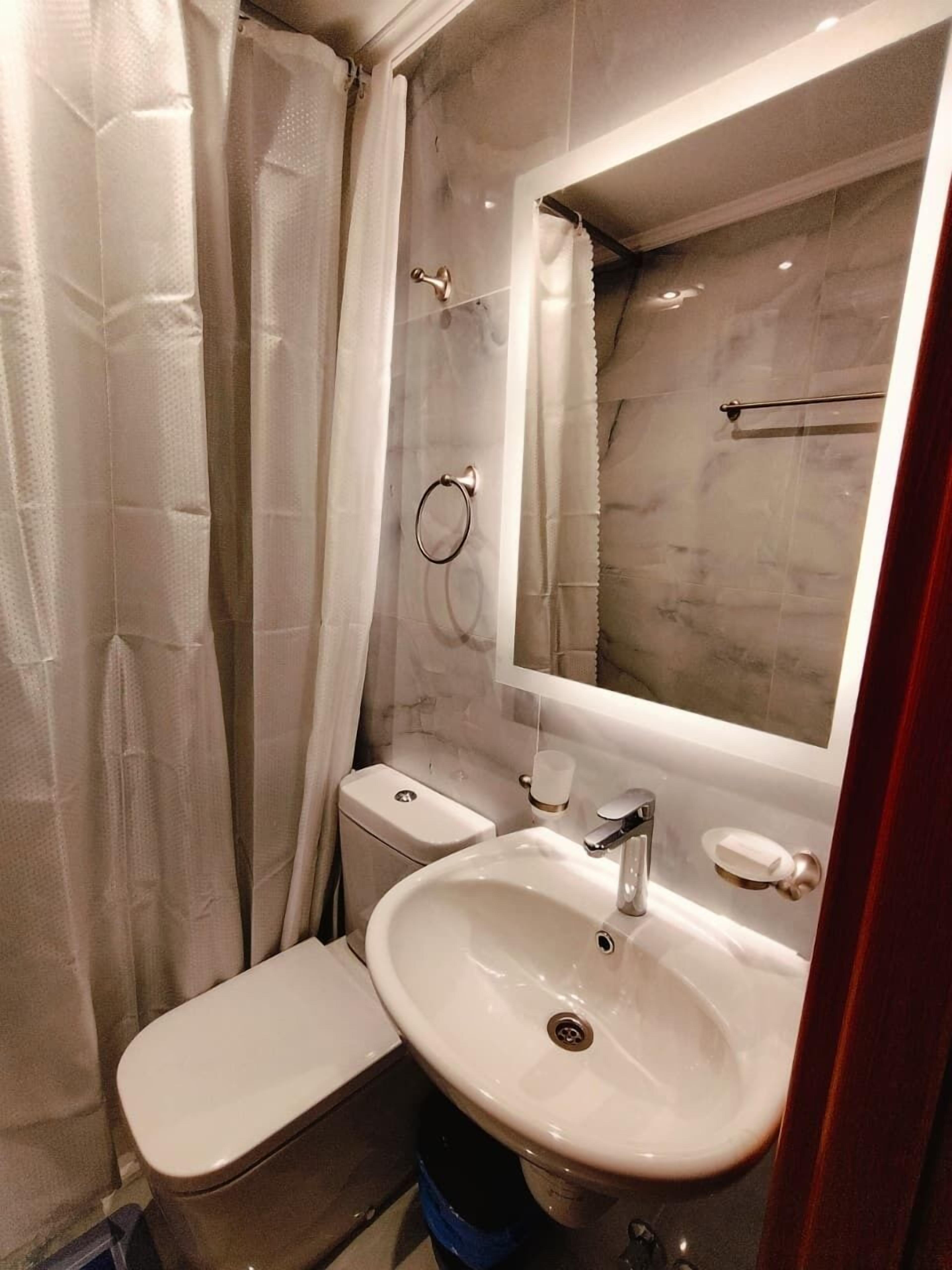 Un baño pequeño con inodoro, lavamanos y ducha.