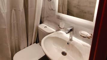 Un baño pequeño con inodoro, lavamanos y ducha.