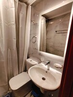 Un baño pequeño con inodoro, lavamanos y ducha.