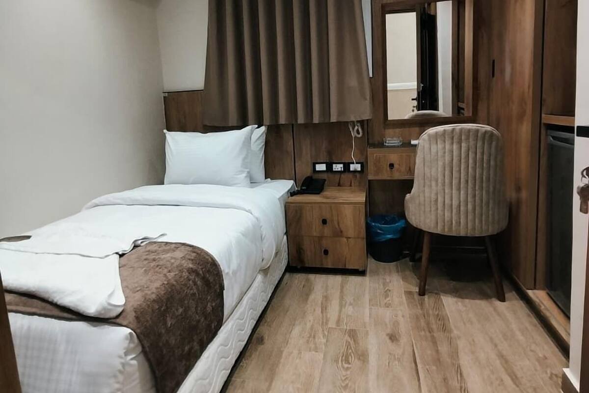 Un dormitorio con cama, mesita de noche, silla y equipo de aire acondicionado.