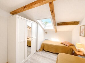 Une chambre avec un puits de lumière, un lit, un bureau avec une lampe et une armoire.