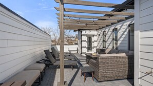 Eine überdachte Terrasse mit Gartenmöbeln, darunter Sofas und Bänke, sowie einer Pergola.