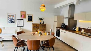 Une cuisine moderne dotée d’un îlot central, de meubles blancs et d’un coin repas avec une table ronde et des chaises.