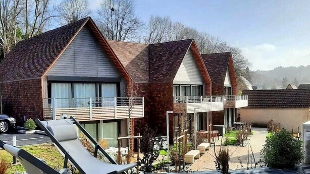 Un bâtiment moderne doté de nombreux balcons et d’un espace extérieur couvert aménagé avec des sièges.