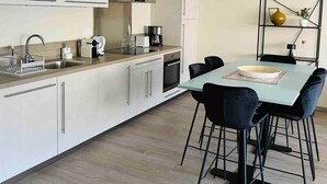 Una cucina moderna con mobili bianchi, forno integrato e zona pranzo con tavolo e sedie.