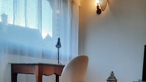 Un soggiorno moderno con un tavolo di legno, una sedia bianca, un televisore su un mobile bianco e una lanterna decorativa.