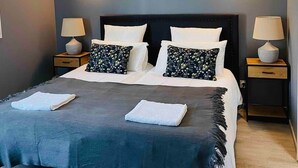 Una camera da letto moderna con una testiera scura, due comodini con lampade e un letto grande con una coperta scura.