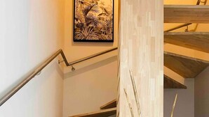 A staircase with wooden steps and a metal handrail, leading to a landing with a framed artwork and a vase with decorative sticks. - Le Spicy 2 minutes historical center parking (Sarlat-la-Canéda)