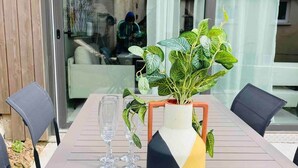 A modern outdoor dining area with a wooden table, two chairs, a potted plant, and a vase. - Le Spicy 2 minutes historical center parking (Sarlat-la-Canéda)