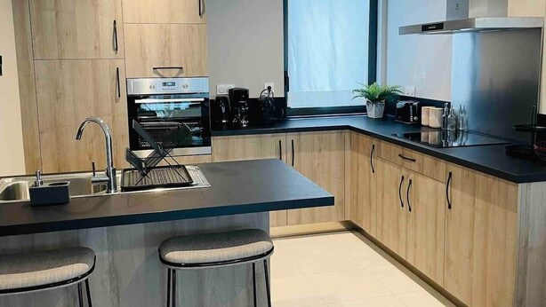 A modern kitchen with a central island, stainless steel appliances, and wooden cabinetry. - Le Spicy 2 minutes historical center parking (Sarlat-la-Canéda)