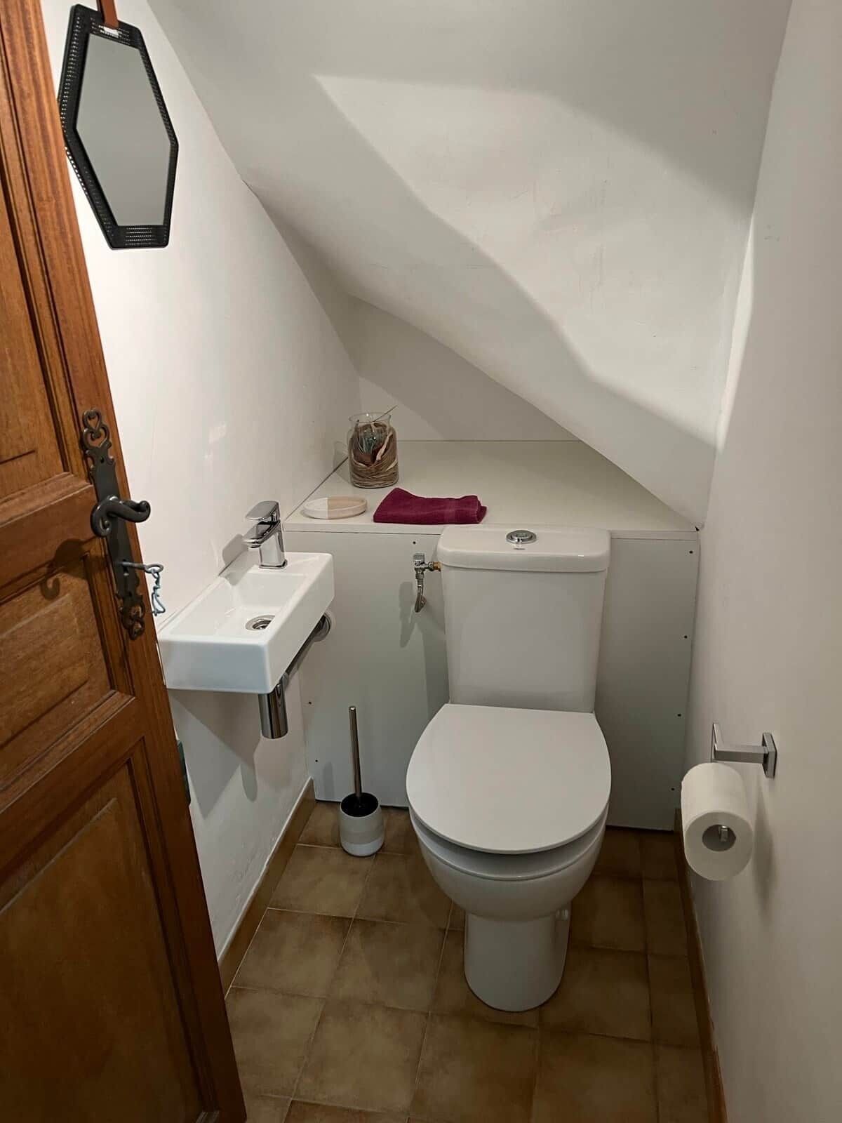 A small, compact bathroom with a toilet, sink, and a mirror.