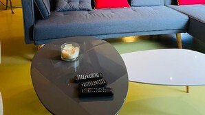 A modern living room with a curved sofa, a round coffee table, and a spiral staircase. - Atypical pool house in a bucolic setting. (Campagnac-lès-Quercy)