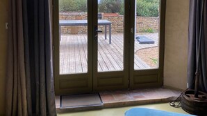 A room with a bed, a wooden deck, and a sliding glass door leading to an outdoor area. - Atypical pool house in a bucolic setting. (Campagnac-lès-Quercy)