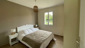 A bedroom with a bed, nightstands, a hanging light, and a window.