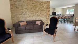 A living room with a stone wall, a brown sofa, and two armchairs.