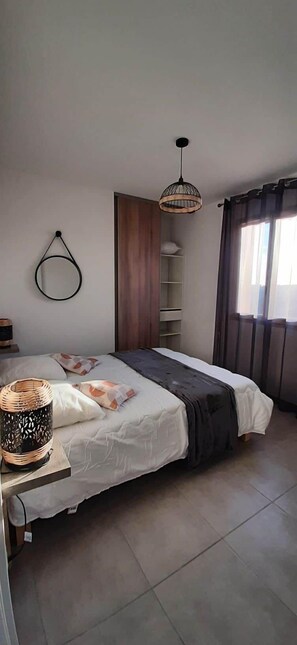 A bedroom with a bed, a hanging light fixture, a shelf unit, and a window with curtains. - Quiet house* Valley view* Near Sarlat (Saint-André-d'Allas)