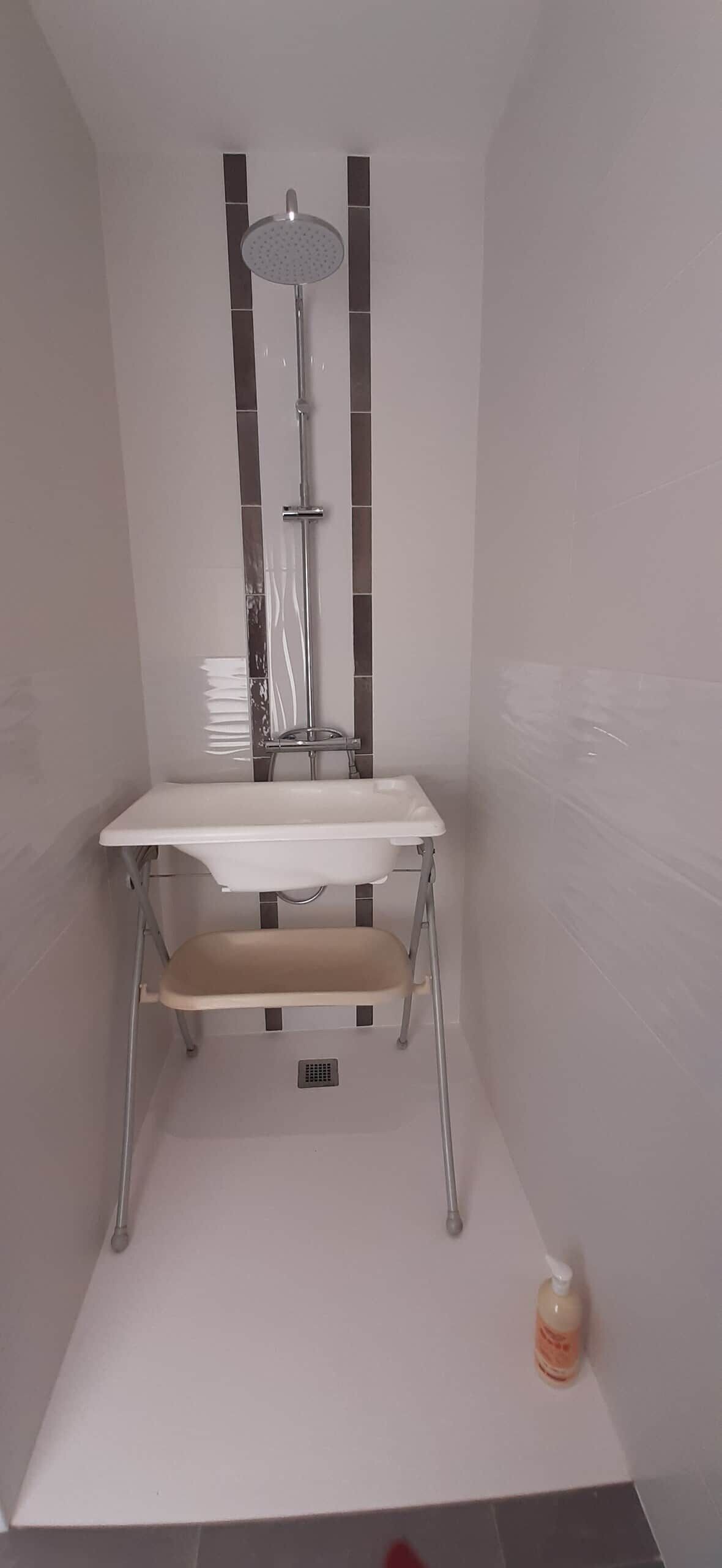 Ein Badezimmer mit einem weißen Waschbecken, einer Handbrause und einer Seifenspender.