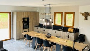 A modern kitchen with a central island, black chairs, and a dining table. - Villa with pool and view of Château de Beynac (Castelnaud-la-Chapelle)