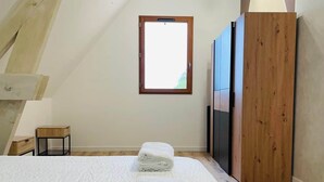 A bedroom with a large bed, a wooden wardrobe, a small table, and a window with natural light. - Villa with pool and view of Château de Beynac (Castelnaud-la-Chapelle)