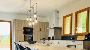 A modern kitchen with a large dining table, black chairs, and wooden cabinets. - Villa with pool and view of Château de Beynac (Castelnaud-la-Chapelle)