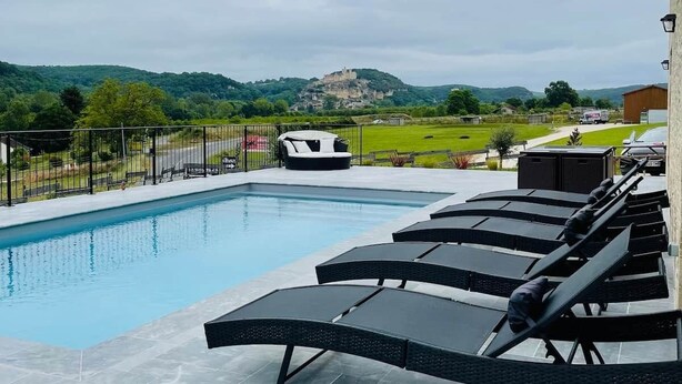 A swimming pool with lounge chairs, a view of a hill with a castle, and a clear sky. - Villa with pool and view of Château de Beynac (Castelnaud-la-Chapelle)