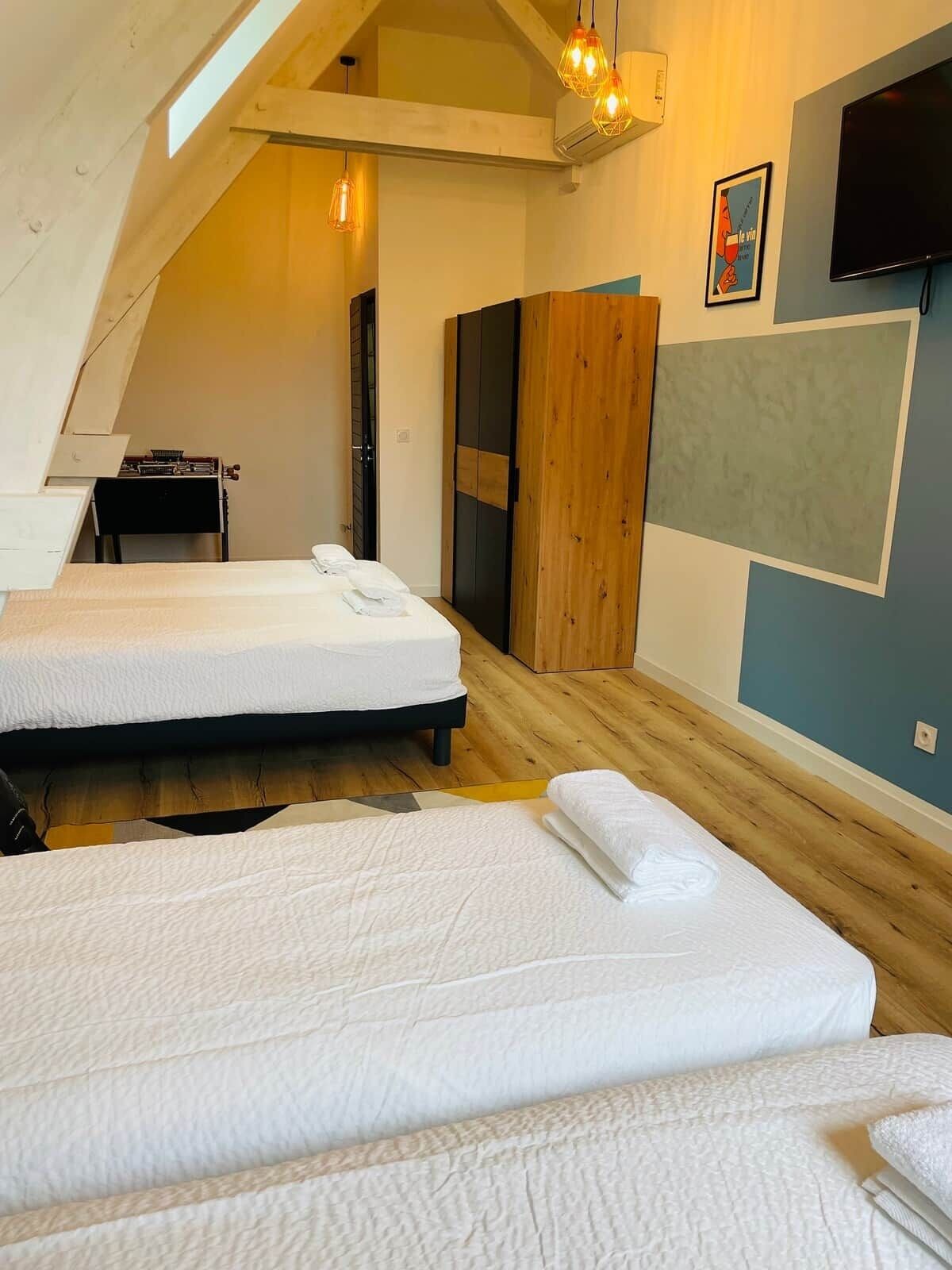 Quarto com duas camas, uma escrivaninha e uma televisão.