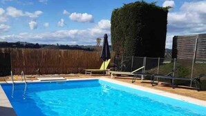 A rectangular swimming pool with clear blue water, surrounded by a wooden deck and a tall hedge. - Villa*Piscine*Proche Sarlat (Proissans)