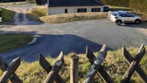 A rural property with a gravel driveway, a white building with a dark roof, and a parked car. - Villa*Piscine*Proche Sarlat (Proissans)