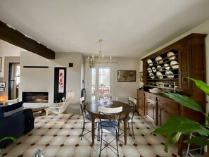 A dining area with a round table and chairs, a chandelier, and a cabinet with dishes. - Peaceful house with parking - 6 guests (Larressore)