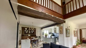 Ein Wohnzimmer mit einem dunklen Sofa, einem Holzstuhl und einem Essbereich inklusive Holzschrank und einer Kronleuchter.