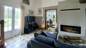Ein Wohnzimmer mit einer Couch, einem Kamin und einem Fernseher.