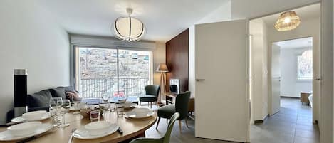 A modern dining area with a round table set for four, a sofa, and a view of a snowy landscape through large windows.