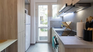 A modern kitchen with wooden cabinets, a built-in oven, a sink, and a window providing a view of the outside. - Daedalus Minimal 1bedroom Bliss (Athina)