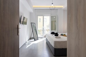 A modern hotel room with a bed, a flat-screen TV, a large window, and a door. - Daedalus Minimal 1bedroom Bliss (Athina)